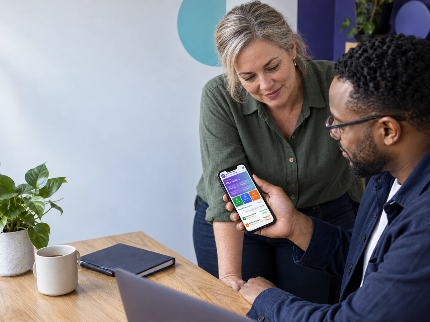 Two people looking at a phone held between them in a working space